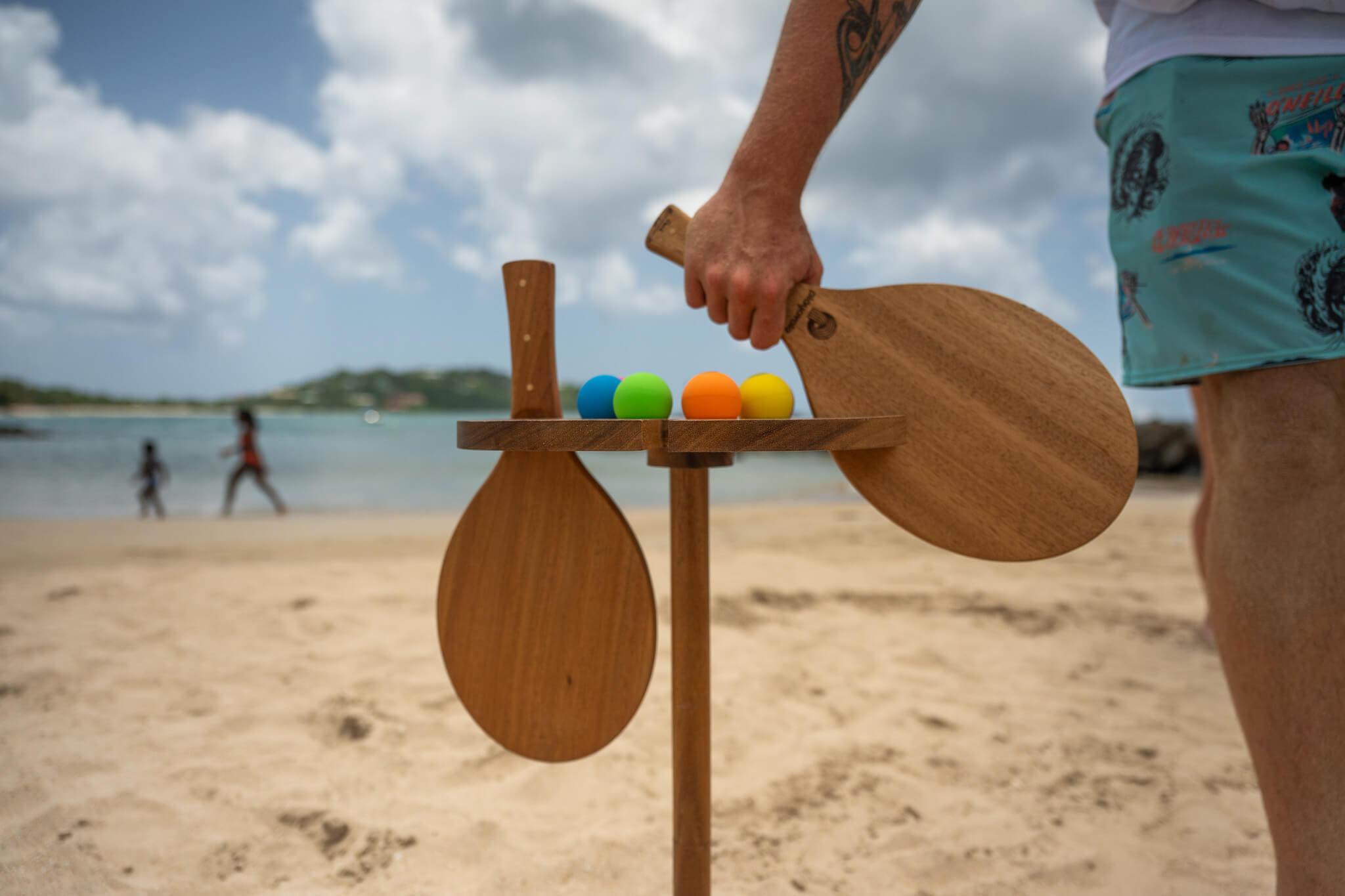 Playa table with view of the beach and person taking one teak vole paddle.