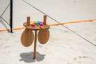 Playa Table with Vole Drops and two Teak Vole Paddles next to Rally Court